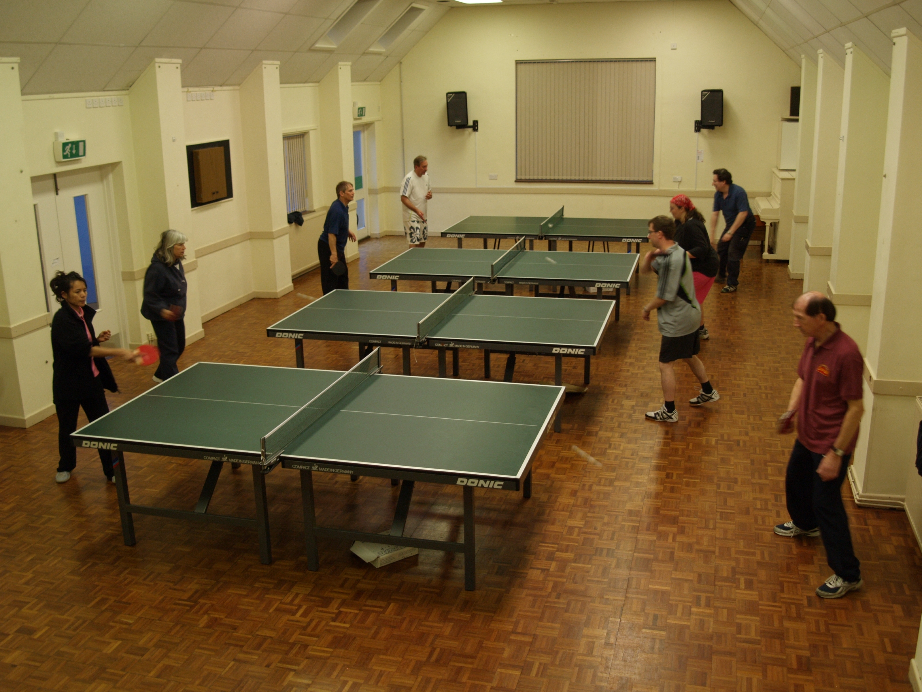 hall with four table tennis tables in use